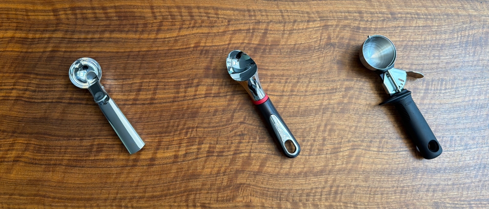 Drei Eisportionierer liegen nebeneinander auf einem Tisch