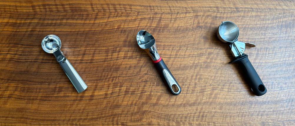 Drei Eisportionierer liegen nebeneinander auf einem Tisch