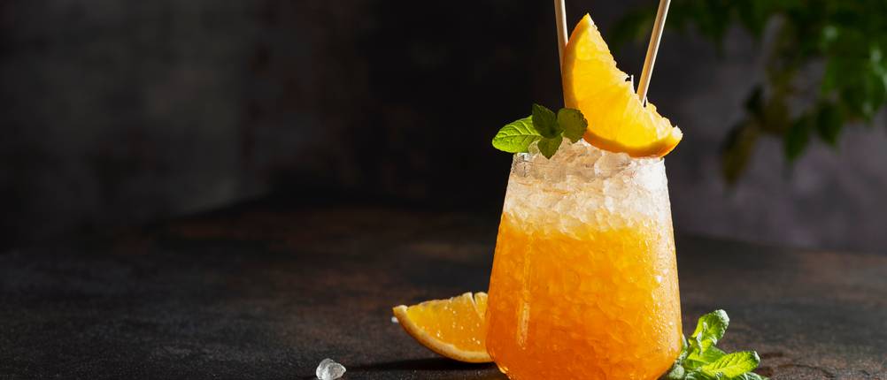 Eiswürfelbeutel im Test: Oranger Longdrink mit Crushed Ice auf dunklem Untergrund
