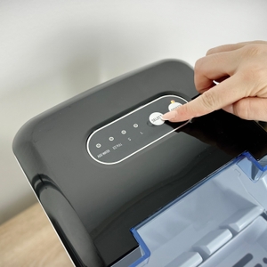 Eine Hand drückt den Power-Knopf der Klarstein On-The-Rocks Eiswürfelmaschine. Die LED-Anzeige zeigt den Betriebsstatus.