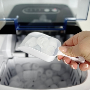 Zubehör der Klarstein On-The-Rocks mit weißer Eisschaufel und Bedienungsanleitung auf hellem Untergrund.