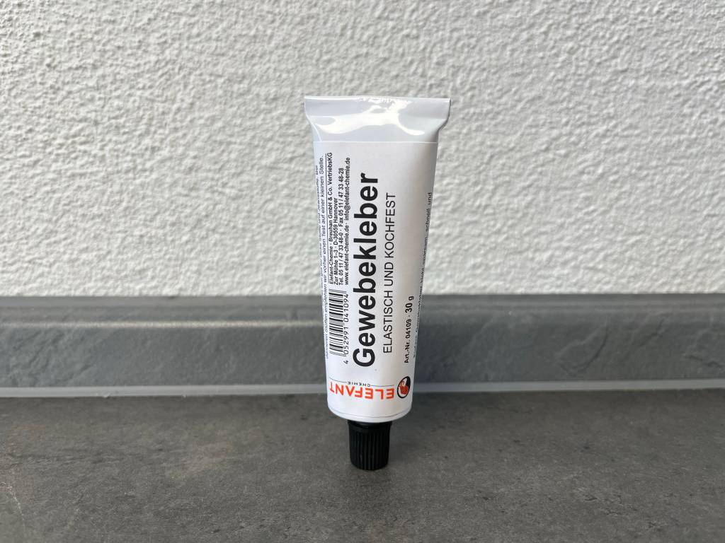 Stoffkleber in einer weißen Tube vor einer Wand