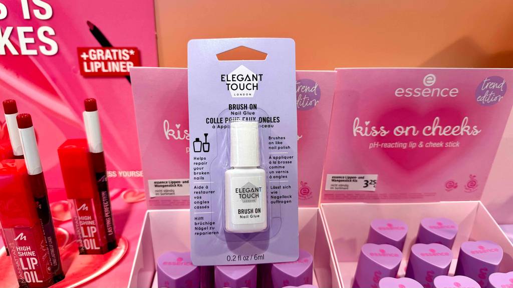 Eine 6-ml-Flasche mit getestetem Nagelkleber im Test ist eingeschweißt in der Verpackung im Kosmetikbereich eines Drogeriemarktes.