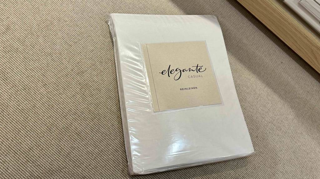 Leinen-Bettwäsche im Test liegt in der Originalverpackung auf einem beigefarbenen Gewebe.