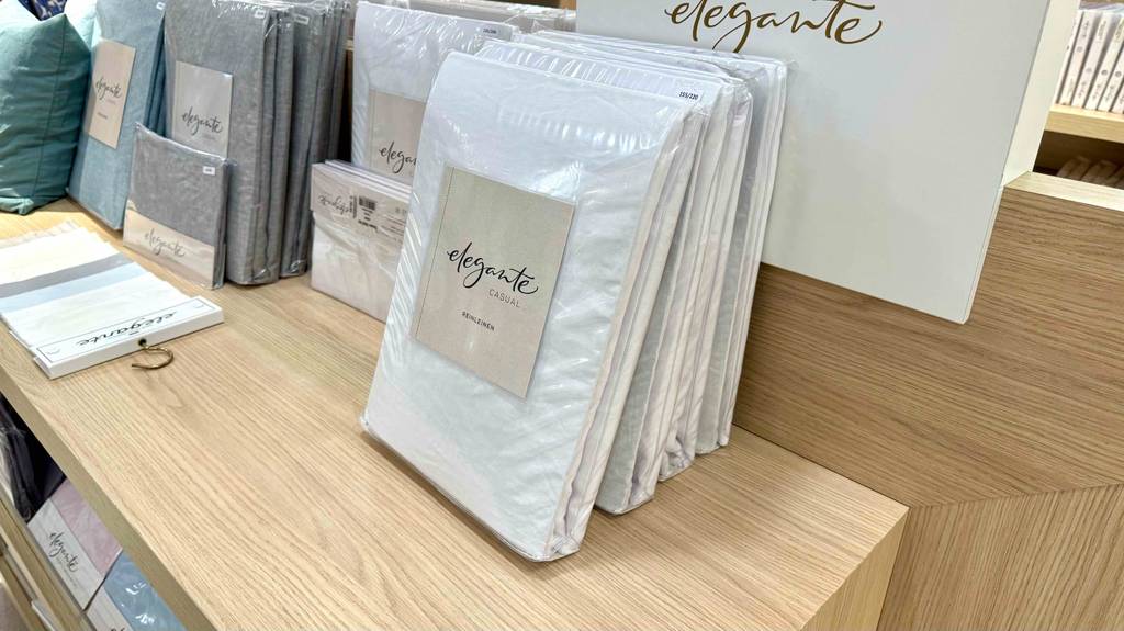 Getestete Leinen-Bettwäsche in der Originalverpackung der Marke Elegante steht auf einem Ausstellungsregal.