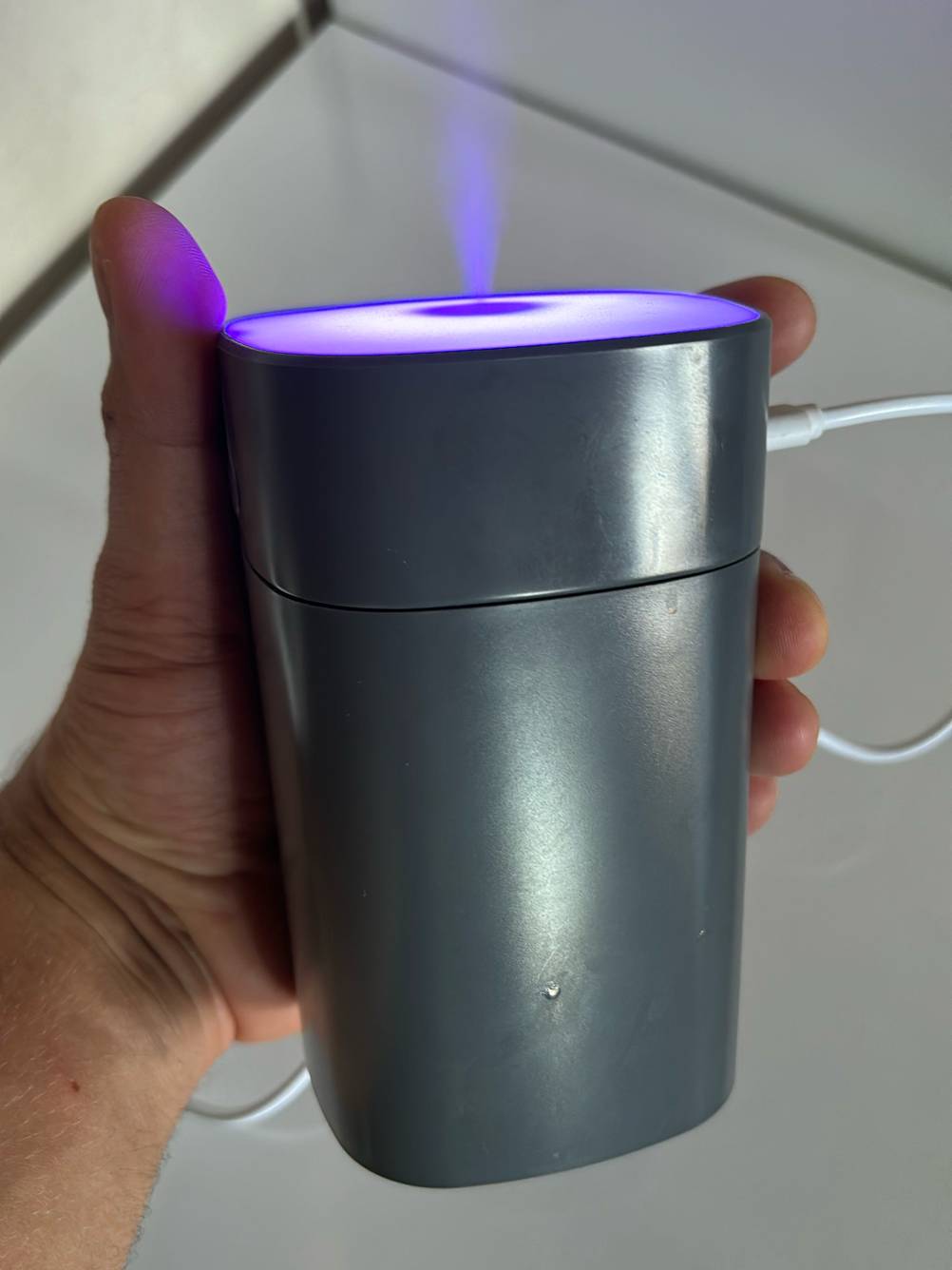 Elektrische Duftlampe-Test: Eine Hand hält das Gerät vor einer helle Fläche, im Fokus der Dampf der austritt.