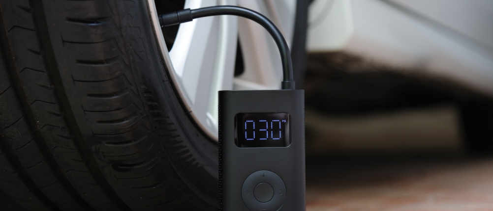 Ein elektrischer Luftkompressor pumpt einen Autoreifen auf und zeigt 30 PSI auf dem Display an.