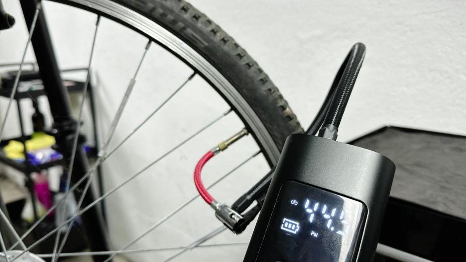 Die Neakhmer Luftkompressor Fahrradpumpe pumpt einen Reifen auf. Das Display zeigt den aktuellen Druck in PSI an.