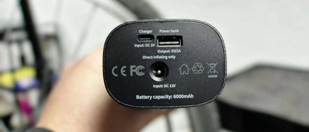 Die Anschlüsse der Neakhmer Luftkompressor Fahrradpumpe sind sichtbar. USB- und DC-Anschlüsse ermöglichen das Laden und die Nutzung als Powerbank.