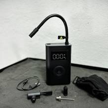 Der Lieferumfang der Xiaomi Fahrradpumpe ist abgebildet. Enthalten sind die Pumpe, ein USB-Ladekabel und verschiedene Adapter.
