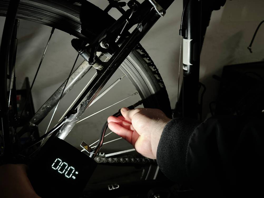 Die integrierte LED-Taschenlampe der Xiaomi-Fahrradpumpe beleuchtet ein Fahrradventil im Dunkeln.