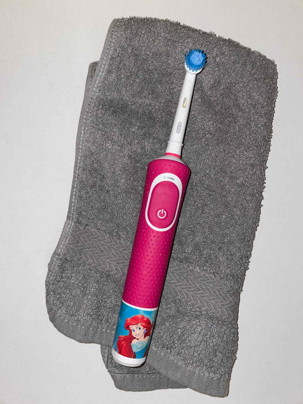 Eine elektrische Kinderzahnbürste im Test liegt auf einem grauen Handtuch.
