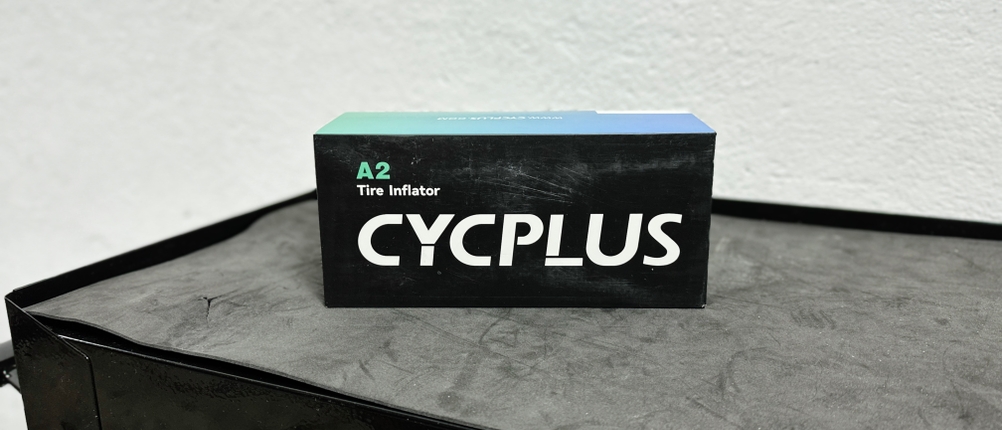 Die Verpackung der Cycplus elektrische Luftpumpe auf einer Werkbank. Das Design hebt das kompakte Format der Pumpe hervor.