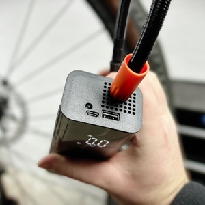 Eine Hand hält die Zoruman CZK-3686 und zeigt die Anschlüsse für USB- und USB-C-Verbindungen. Der Luftschlauch ist seitlich befestigt.