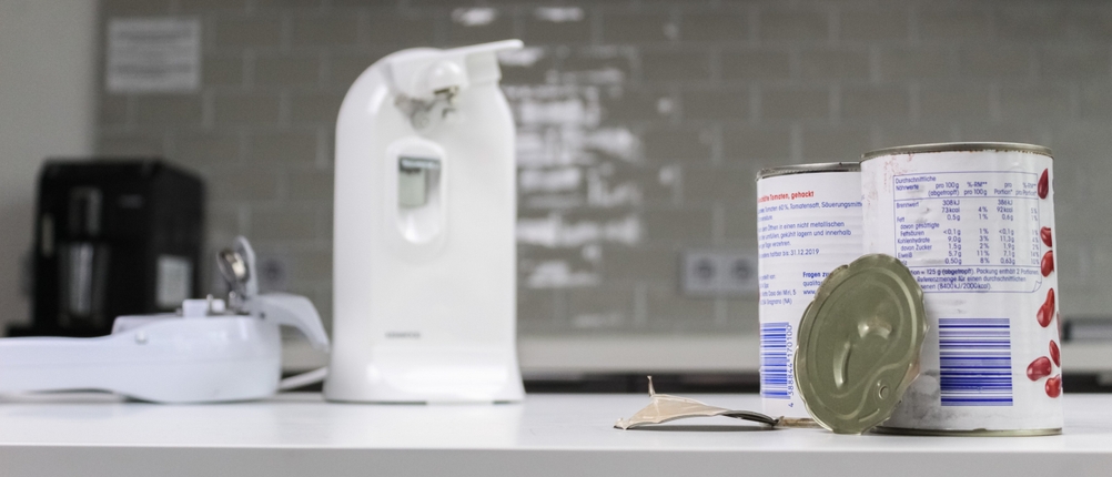 Geöffnete Dosen stehen neben einem großen elektrischen Dosenöffner in der Küche.