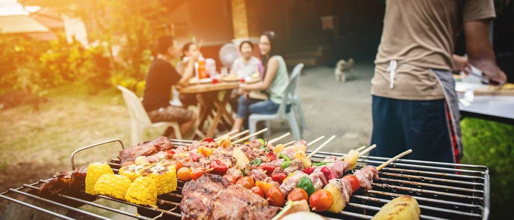 Grill mit Grill gut vor dem Hintergrund einer Gruppe rund um einen Essenstisch.