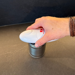 Eine Hand setzt den elektrischen Kitchen-Mama-Auto-Dosenöffner auf eine Dose