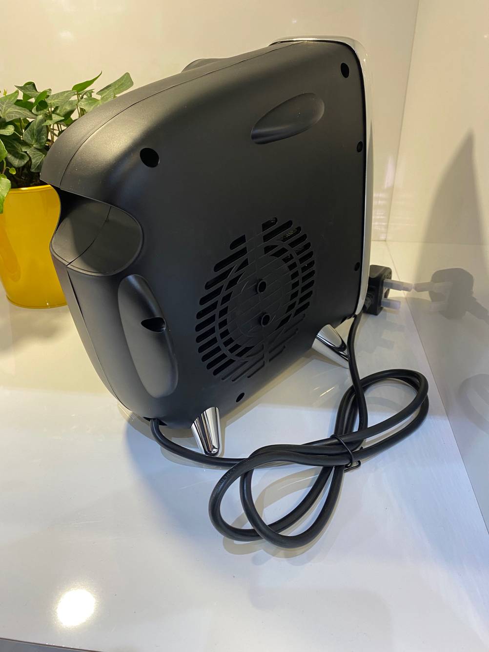 Seitenansicht einer getesteten Elektroheizung mit Lüftungsschlitzen und einem Stromkabel auf einer hellen Fläche.