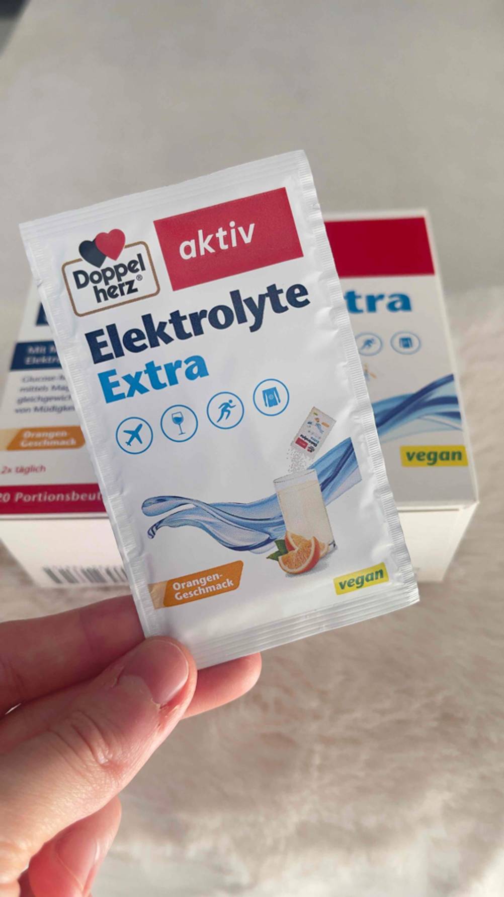 Eine Hand hält ein Päckchen des getesteten Elektrolyt-Pulvers vor die Packung.