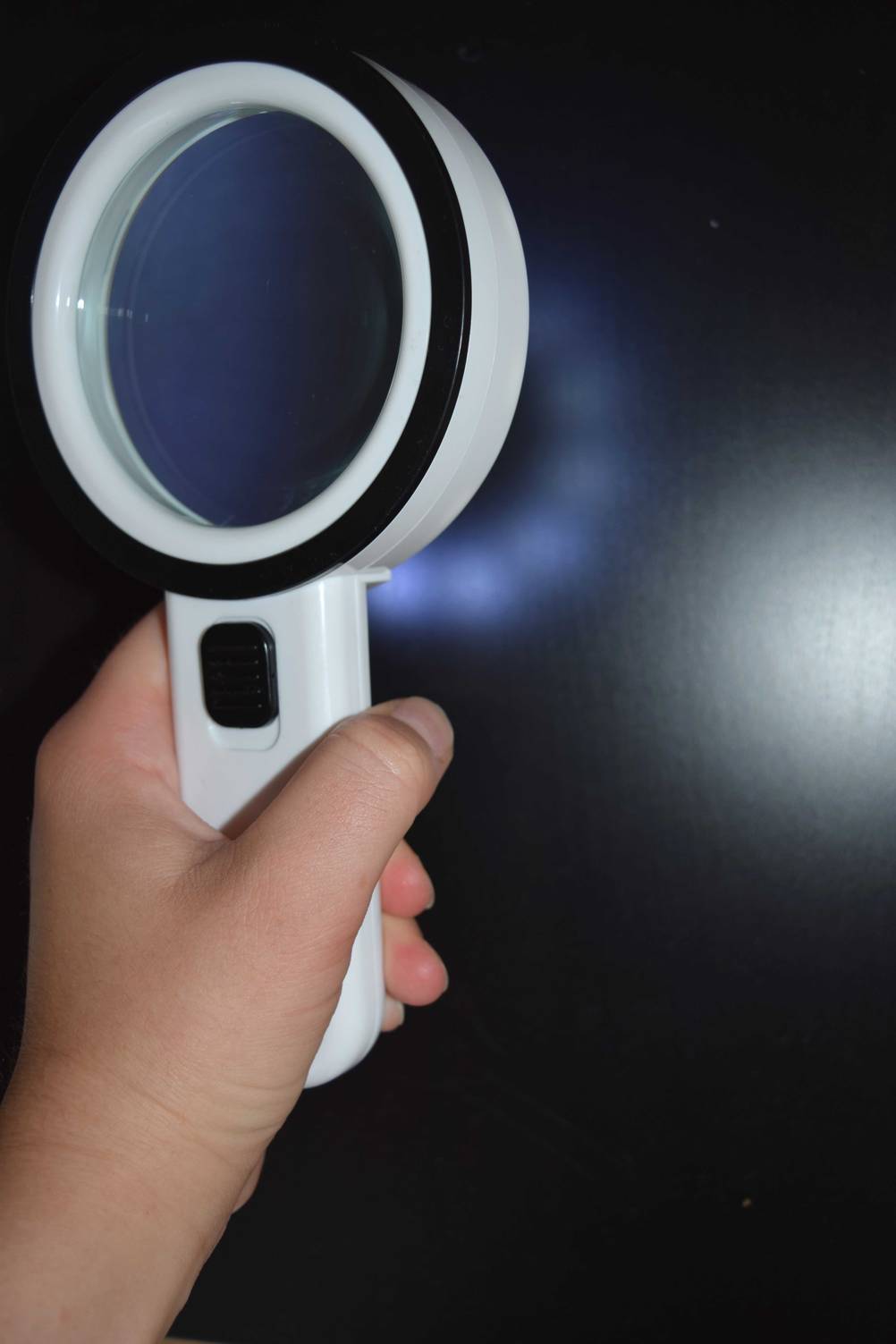 elektronische Lupe mit angeschaltetem Licht in einer Hand.