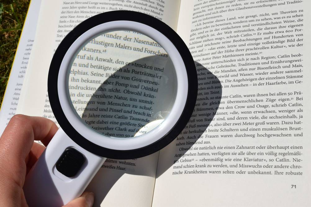 Eine Hand hält eine elektronische Lupe im Test vor ein Buch.