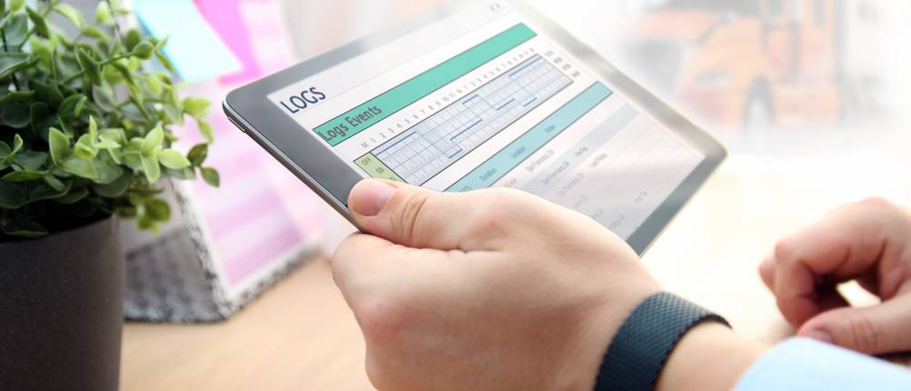 Elektronisches-Fahrtenbuch-Test: Ein Mann hält ein Tablet mit den Fahrtdaten eines Fahrers in der Hand.