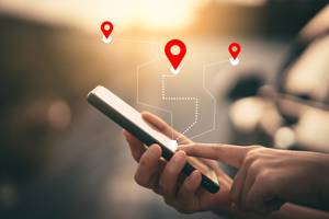 Elektronische Fahrtenbücher im Test: Eine Person hält ein Smartphone in der Hand, virtuell werden mehrere Orts-Symbole eingeblendet.