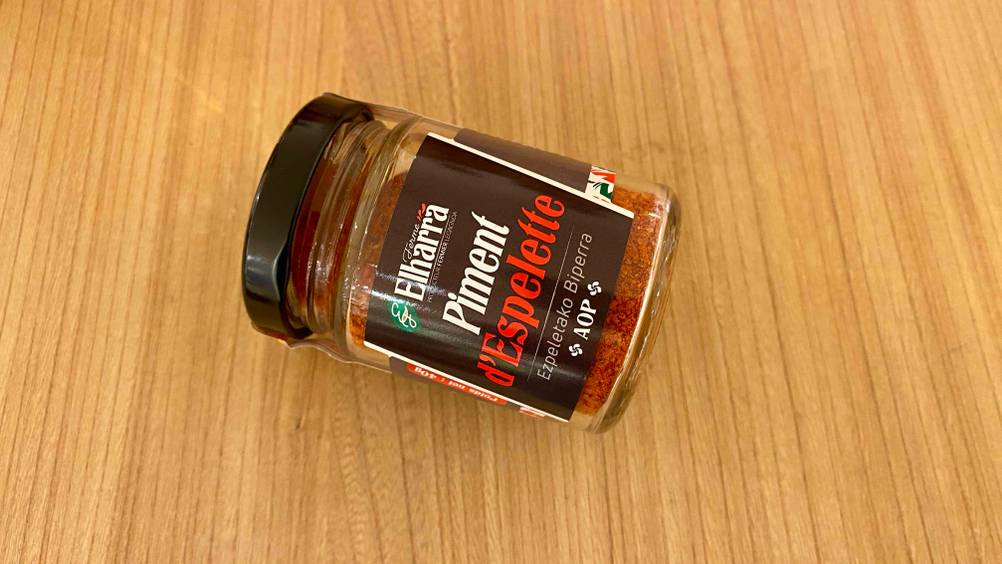 Im Test: Ein Glas Piment d'Espelette liegt horizontal auf einer Holzfläche.