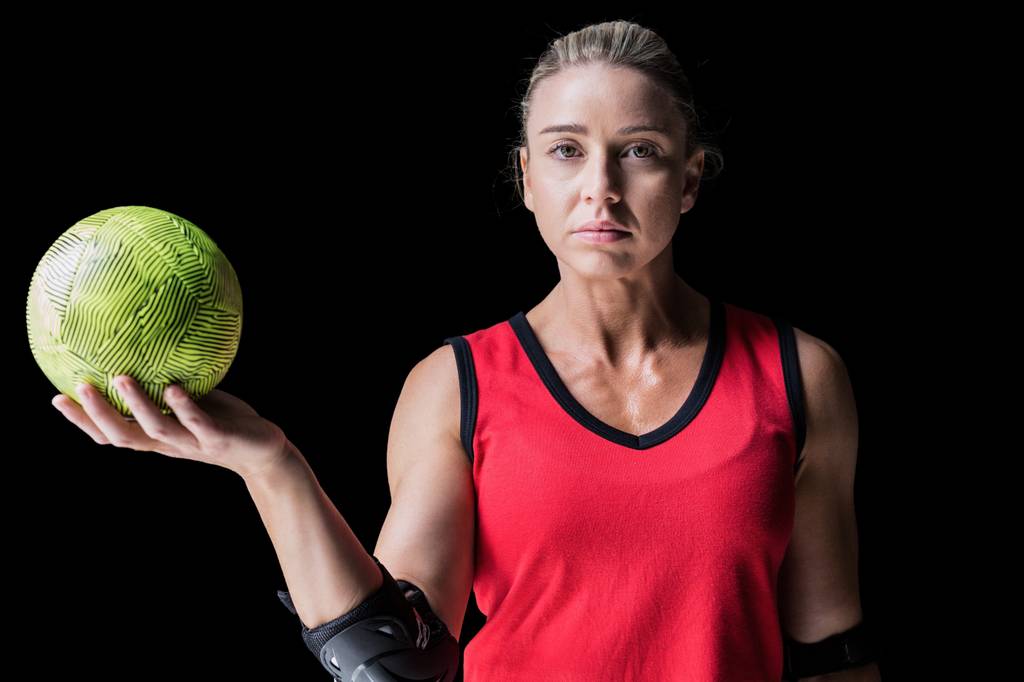 Ellenbogenschoner-Test: Eine Frau im Sporttrikot hält einen Handball in der Hand und trägt an beiden Ellenbogen einen Schoner. 