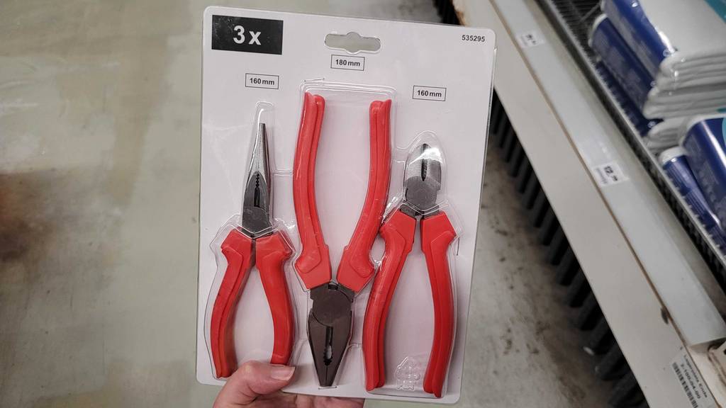 Eine Hand hält ein im Blister verpacktes Zangen-Set zum Testen.