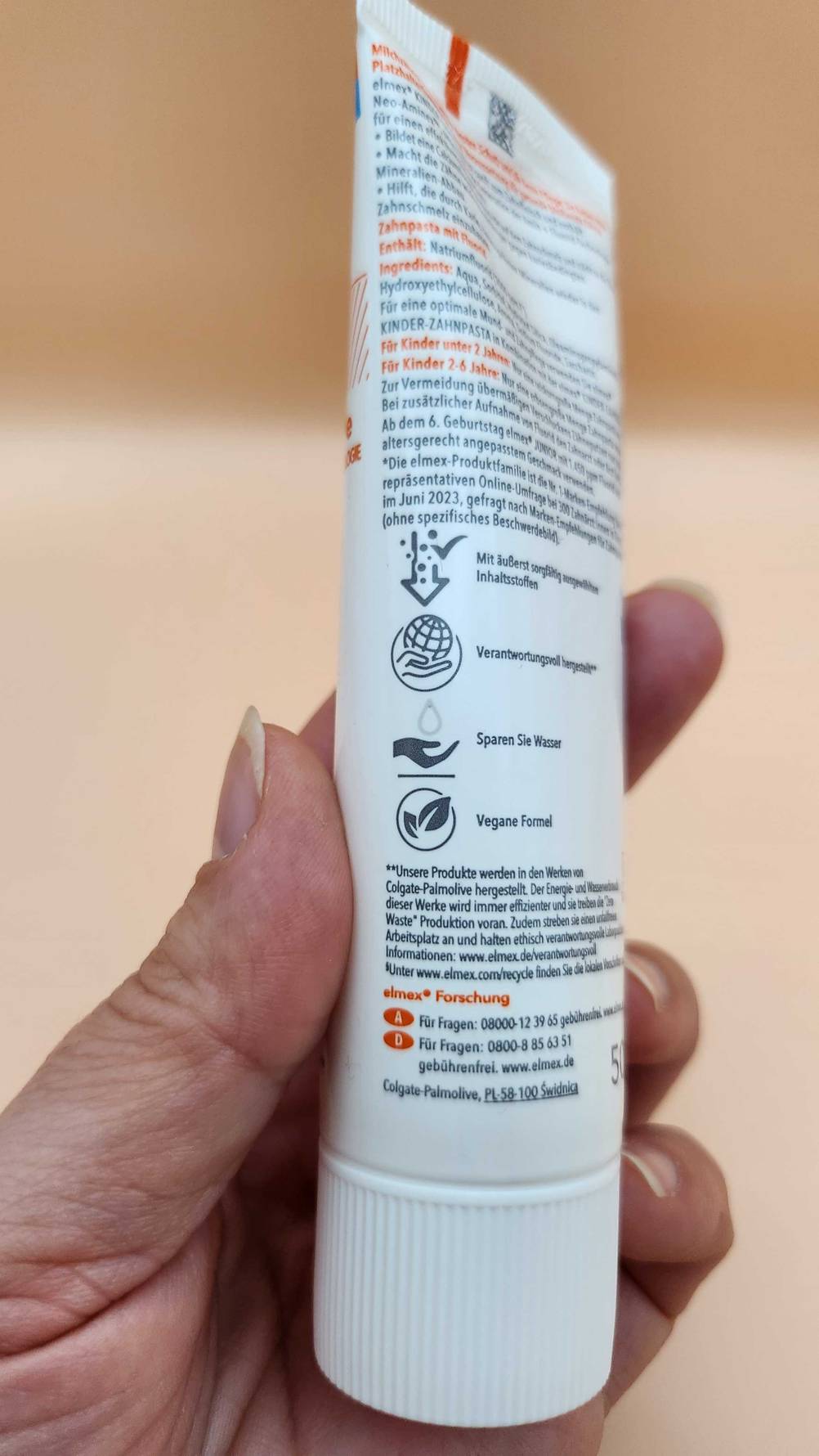 Im Test: Eine Hand hält eine Tube Elmex Zahnpasta mit der Rückseite nach vorn.