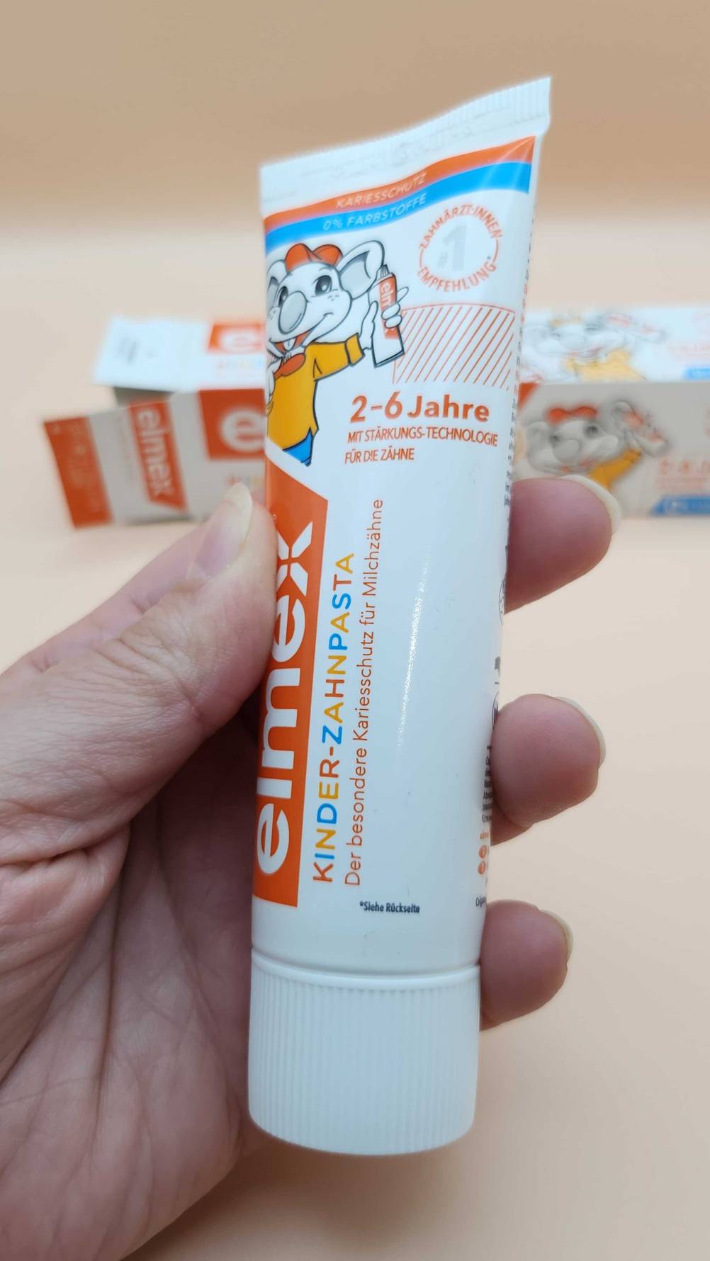 Im Test: Eine Hand hält eine Tube Elmex Zahnpasta für Kinder.