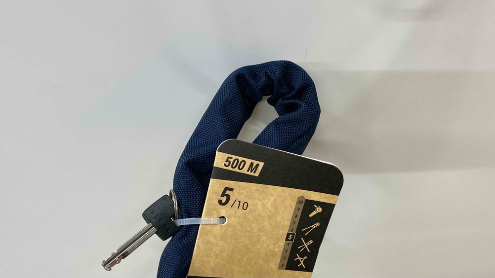 Nahaufnahme des Stoffüberzuges des Kettenschlosses mit Label und Schlüssel.