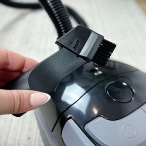 Eine Hand hält die umklappbare 2-in-1-Düse des Emerio VE-109959.14 Staubsaugers. Das Gerät ist im Hintergrund leicht verschwommen sichtbar.