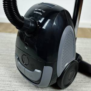 Der Emerio VE-109959.14 Staubsauger steht auf einem Teppich. Sichtbar sind die Seitenbelüftung, Räder und das kompakte Gehäuse.