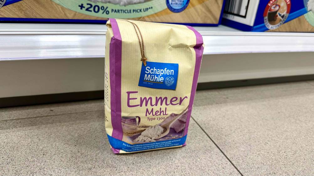 Auf dem Boden vor einem Regal steht eine Packung des getesteten Emmermehls.