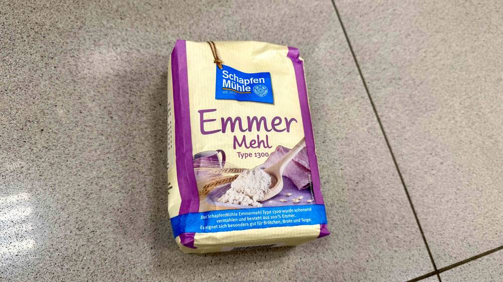 Auf dem Fließenboden liegt eine Packung des getesteten Emmermehls.