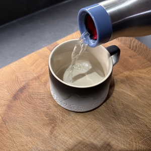 Wasser wird aus der Emsa-Bludrop-Eco-Isolier-Trinkflasche in eine Tasse gegossen