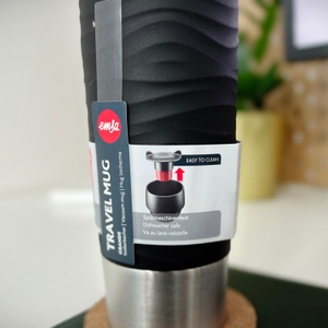 Informationen über den Emsa-Waves-Grande-Thermobecher auf einem Schild am Becher. Gezeigt wird die Reinigung.