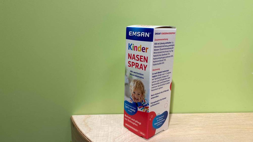 Nasenspray für Kinder im Test: eine Originalverpackung steht vor grüner Wand mit Blick auf Dosierung und Zusammensetzung.