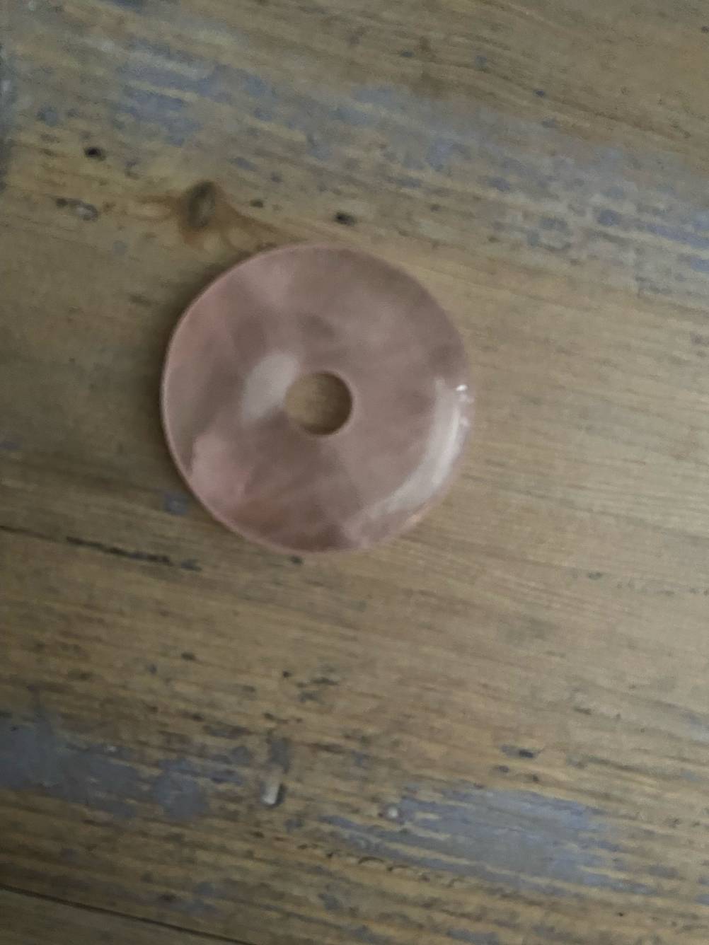 Ein rosa Energiestein im Test auf einer Holzfläche.