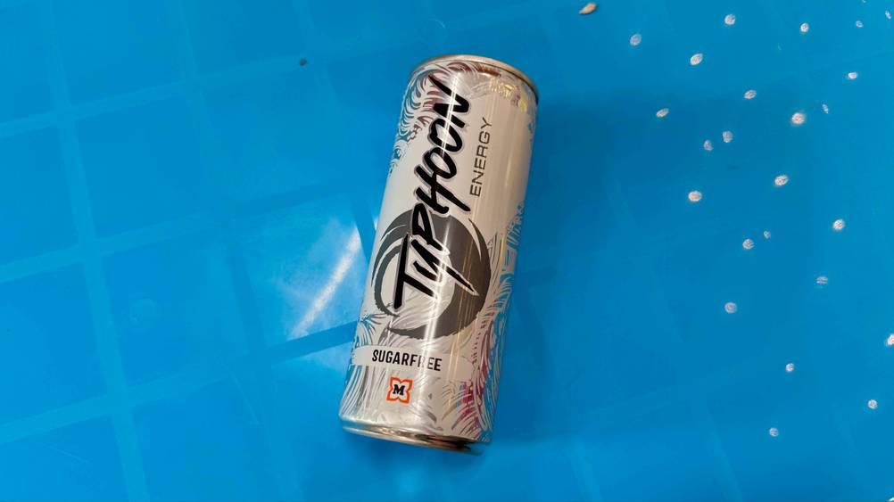 Eine Dose des getesteten Energy-Drink(s)-ohne-Zucker auf einer blauen Fläche liegend.