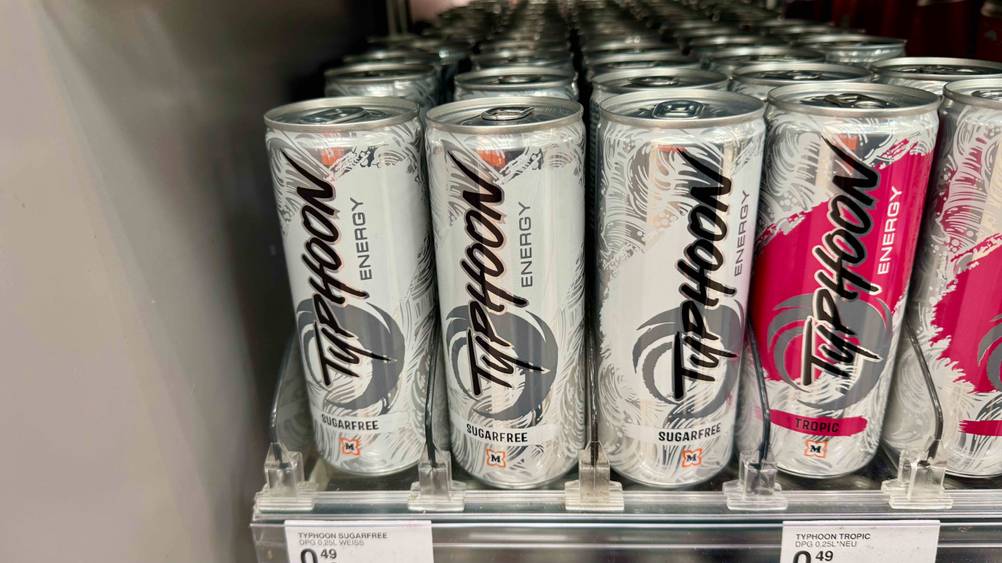 Mehrere Dosen des getesteten Energy-Drink(s)-ohne-Zucker stehen in einem Verkaufsregal neben anderen Sorten.