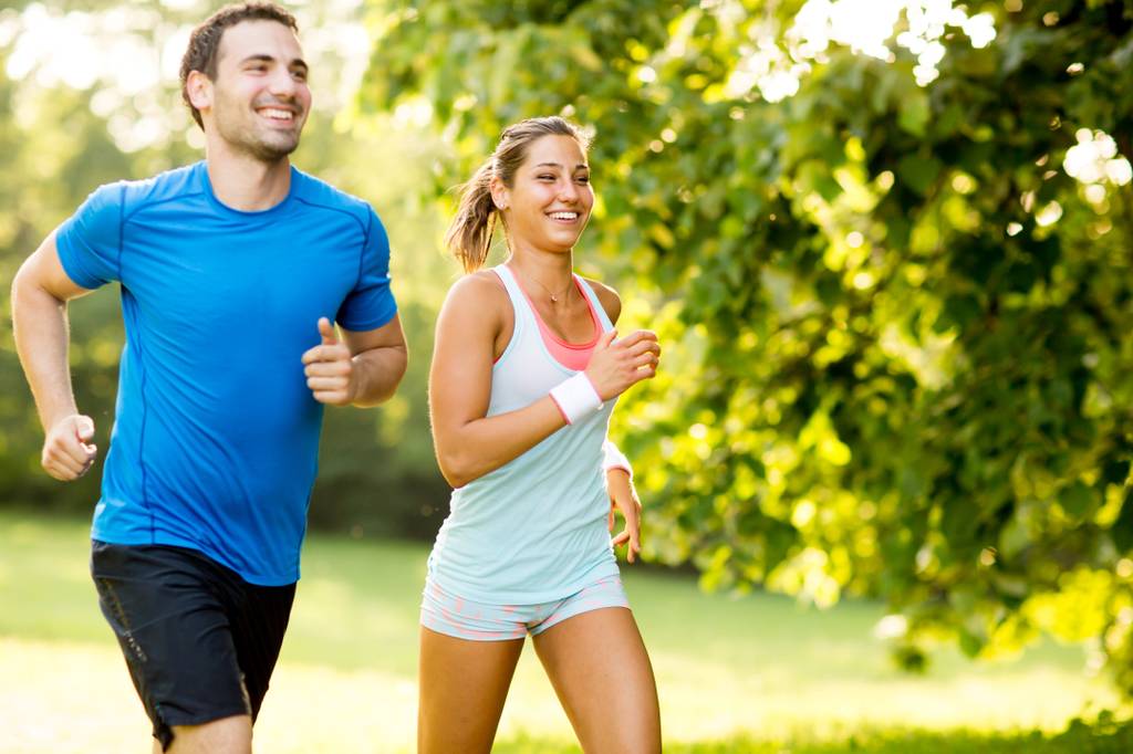 Laufshirt-Test: Frau und Mann laufen gemeinsam durch einen Park.