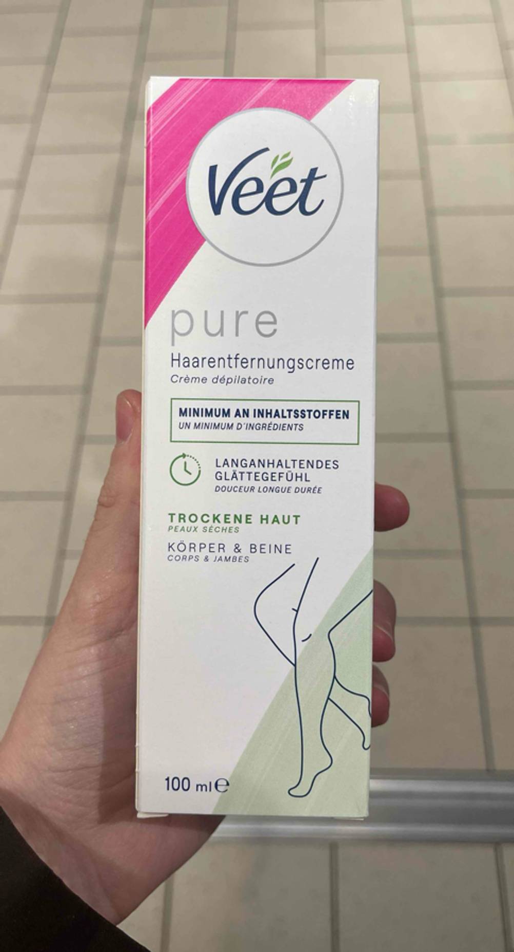 Enthaarungsmittel im Test: Eine Hand hält die Verpackung einer Creme.