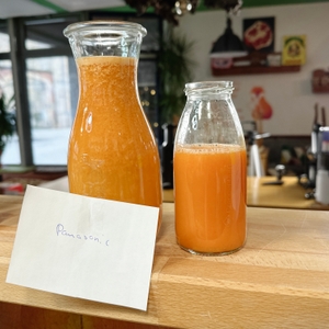 Zwei Glasflaschen mit frisch gepresstem Saft aus dem Panasonic MJ-L700KXE stehen auf einem Tresen.