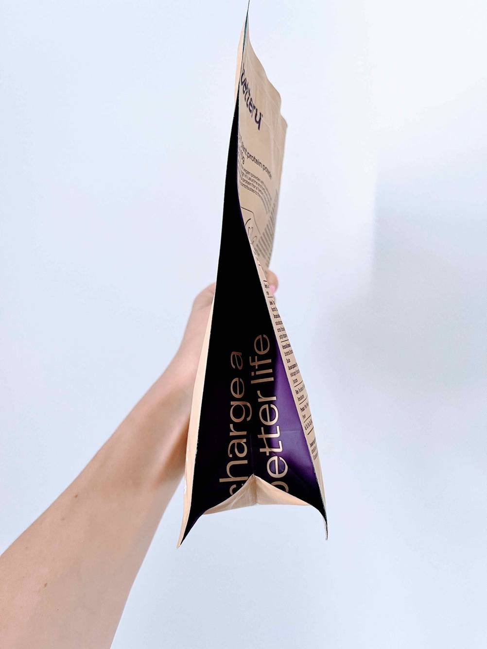 Eine Packung des getesteten Erbsenproteins von der Seite, von einer Hand vor eine helle Wand gehalten.
