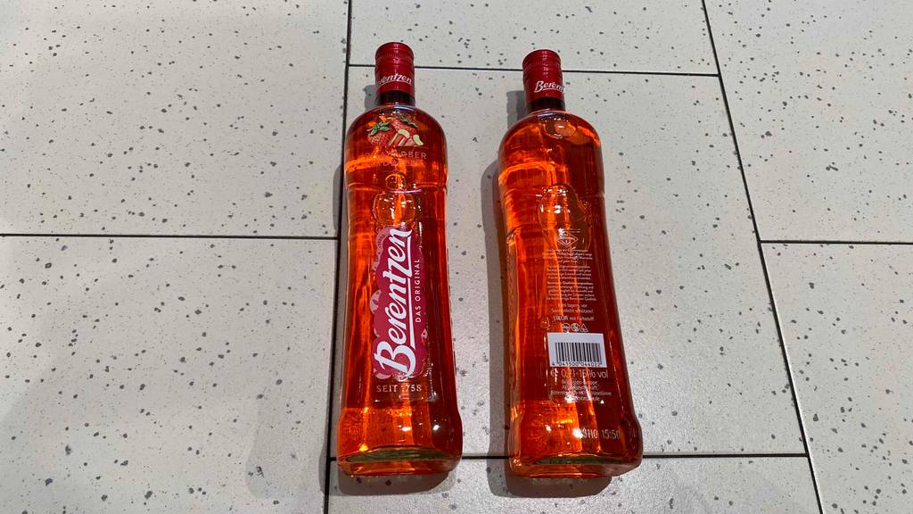 Zwei Flaschen getestete Erdbeerliköre liegen auf dem Boden. 
