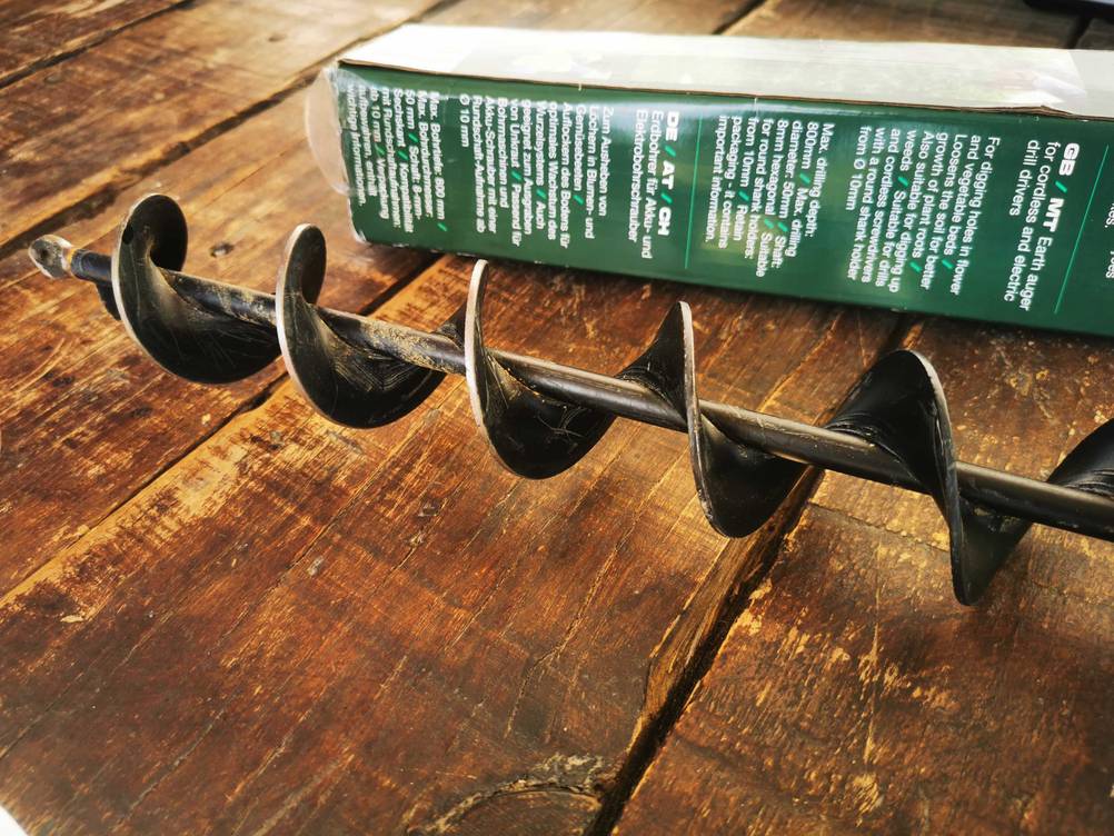 Nahaufnahme des getesteten Erdbohrer für Bohrmaschine auf einem Holztisch vor der Originalverapckung.