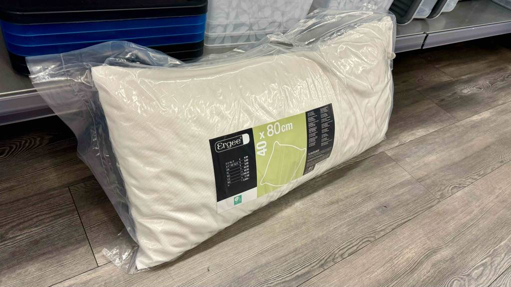 Im Test: Ein in Folie verpacktes Visco-Kissen lehnt auf einem hellen Boden an ein Regal.